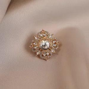 Detailed close-up of a vintage gold-toned crystal floral brooch sparkling rhinestones accessory.