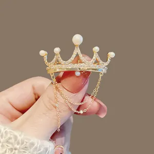 Exquisite crown brooch detail view, featuring sparkling rhinestones, pearls and delicate hanging chains.