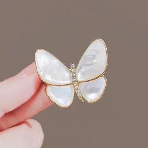 Detailed view of elegant gold butterfly brooch with shell wings and pavé crystals