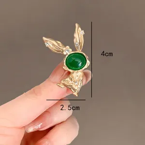 Close-up detail of golden rabbit brooch with green stone showing 4cm x 2.5cm dimensions