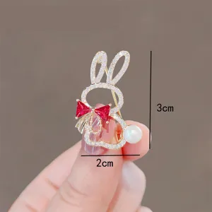 Close-up of a sparkling rabbit brooch with a red bow and pearl, measuring 3x2cm.