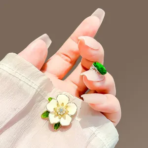 Detailed macro view of an elegant white gardenia flower brooch and green gemstone ring.