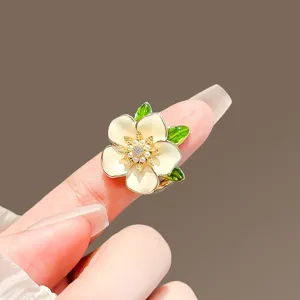 Macro view of elegant gardenia flower brooch featuring pearl center and green leaves