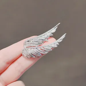 Close-up of luxury crystal-encrusted angel wing feather brooch in silver finish