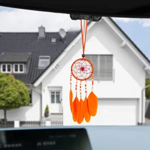 Macro detail of a vibrant orange handmade dreamcatcher hanging from a car rearview mirror