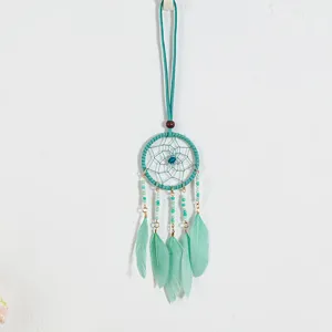 Close-up of a mint green ethnic dreamcatcher pendant showing intricate weave and feathers