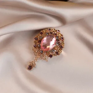 Vintage pink crystal flower brooch with gold tone metal and hanging pendant accessory for women.
