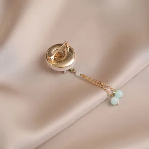 Close-up detail view of vintage style bamboo safety buckle brooch pin with delicate hanging tassels.