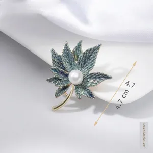 Detail view of an elegant green maple leaf brooch featuring a center pearl accent