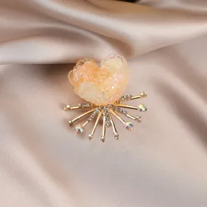 Close-up of a sparkling floral brooch featuring translucent resin petals and crystal rhinestones.