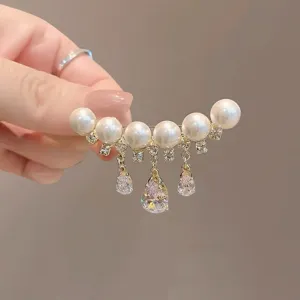 Détail d'une broche en perles de luxe avec des glands en cristal étincelants en forme de goutte