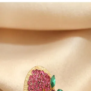 Exquisite rhinestone fruit brooch detail shot, elegant gold tone finish with pink stones.