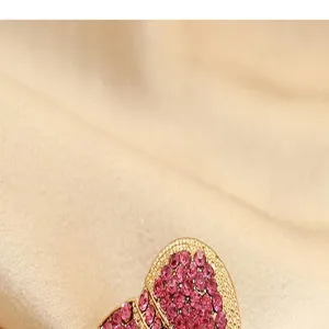 Close-up detail of a sparkling rhinestone heart brooch with intricate golden metal frame.