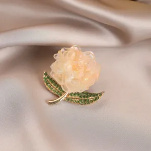 Exquisite translucent flower brooch featuring sparkling green rhinestone leaves and gold base.