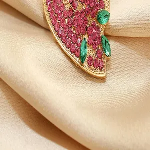 Closeup detail of rhinestone strawberry brooch showing sparkling pink and green crystal texture.