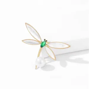 Exquisite dragonfly brooch detail featuring white mother-of-pearl wings and green crystal body.