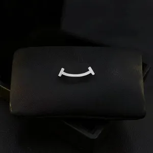 Detailed close-up shot of the elegant silver curved smile brooch on a black display pad.