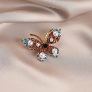 Detailed macro view of an elegant butterfly brooch with rhinestones and pearls on satin.