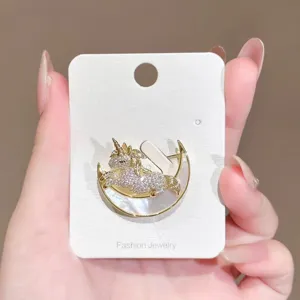 Exquisite rhinestone unicorn brooch detail shot, elegant gold tone crescent moon design.