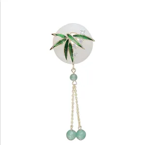 Elegante broche de estilo chino con hoja de bambú, borlas colgantes y brillantes pedrerías.