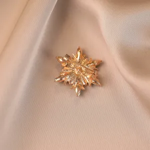 Back view detail of a vintage gold flower brooch with crystal inlay on satin background
