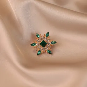 Detailed macro view of vintage flower brooch with green crystals on champagne silk fabric