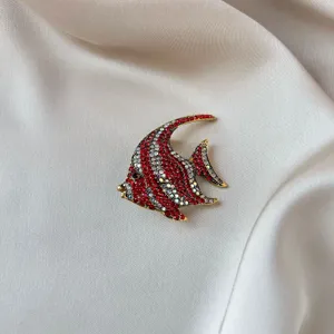 Elegant fish shape brooch encrusted with red and silver crystals on a gold metal base