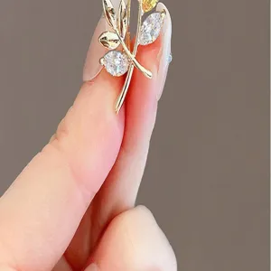 Gold-tone plant leaf rhinestone brooch pin, delicate accessory for women's suit lapel.