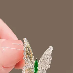 Detailed close-up view of a sparkling butterfly rhinestone brooch with green stone.