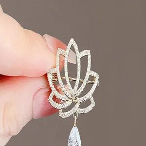 Elegant lotus flower crystal brooch pin with dangling teardrop pendant, gold tone suit accessory.
