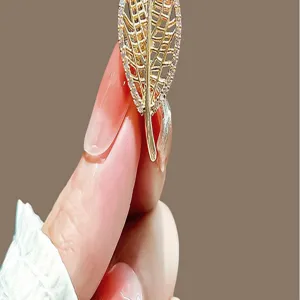 Gold leaf brooch detail showing intricate hollowed design and sparkling micro-set crystal stones.