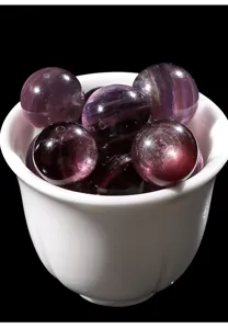 Primer plano de cuentas redondas de lepidolita morada natural en cuenco blanco