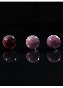 Vista macro de tres cuentas redondas de lepidolita púrpura con reflejos elegantes.