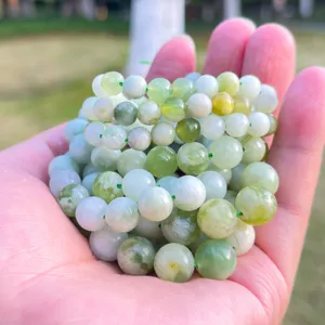 Primo piano di perle in giada naturale verde chiaro e bianco per progetti di gioielli DIY.