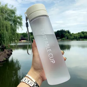 Détail de gourde en plastique givré, couvercle blanc et dragonne, vue sur le lac.