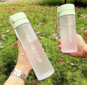 Gros plan de la gourde portable mate avec couvercle vert dans un décor extérieur.