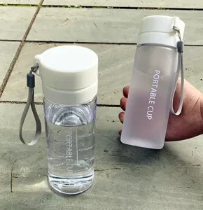 Gros plan de bouteille d'eau de sport en plastique portable avec tasses transparentes.