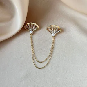 Detail van gouden waaiervormige kraagspeld met dubbele ketting en parelaccent
