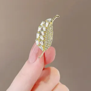 Detail view of an elegant gold leaf-shaped brooch adorned with sparkling crystals