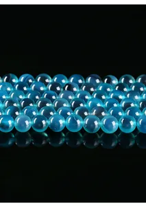 Close-up of translucent blue agate beads arranged on a black reflective surface.