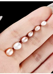 Detailed macro view of natural rice-shaped pink and white freshwater pearls on fingers.