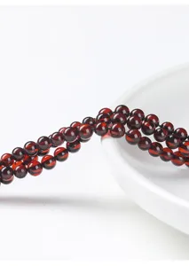 Nahaufnahme von natürlichen tiefroten Blutbernsteinperlen für DIY-Schmuck auf Porzellan