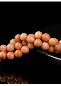 Close-up of natural red amazonite beads showing smooth texture and warm orange tones.