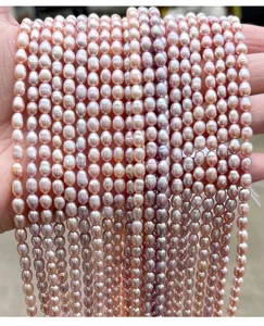 Close-up van strengen natuurlijke roze zoetwater rijstparels voor DIY-sieraden maken.