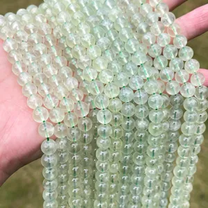Primo piano di perle tonde traslucide in prehnite naturale di colore verde chiaro.