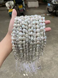Detailed macro shot of white natural Baroque pearl loose beads held in a person's hand