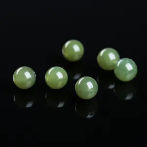 Macro detail of natural green Hetian jade round beads for jewelry making DIY projects.