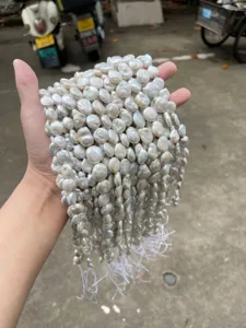 Hand holding clusters of natural baroque pearls for DIY jewelry making
