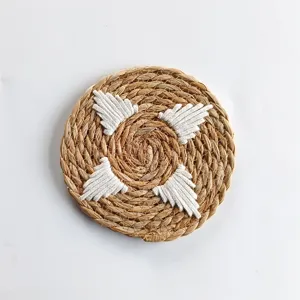 Close-up of a round woven straw placemat with white cotton rope decorative accents.