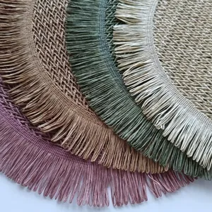 Closeup view of circular paper rope woven placemat with delicate fringe and hollow design.